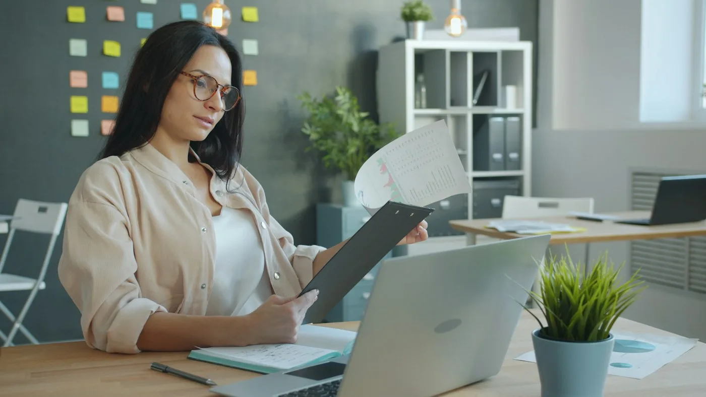 Mulher trabalhando com documentos e notebook em um escritório